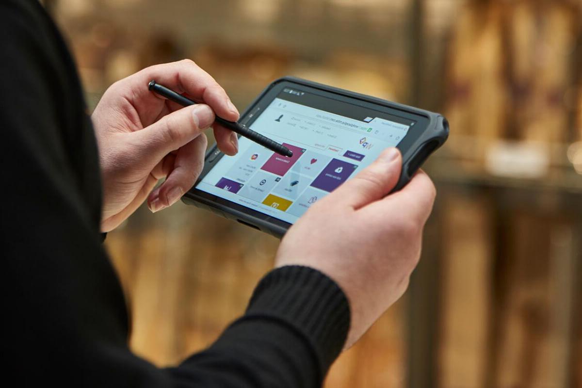 Male security guard in Sainsbury's using Mitie's Merlin security technology system with a stylus